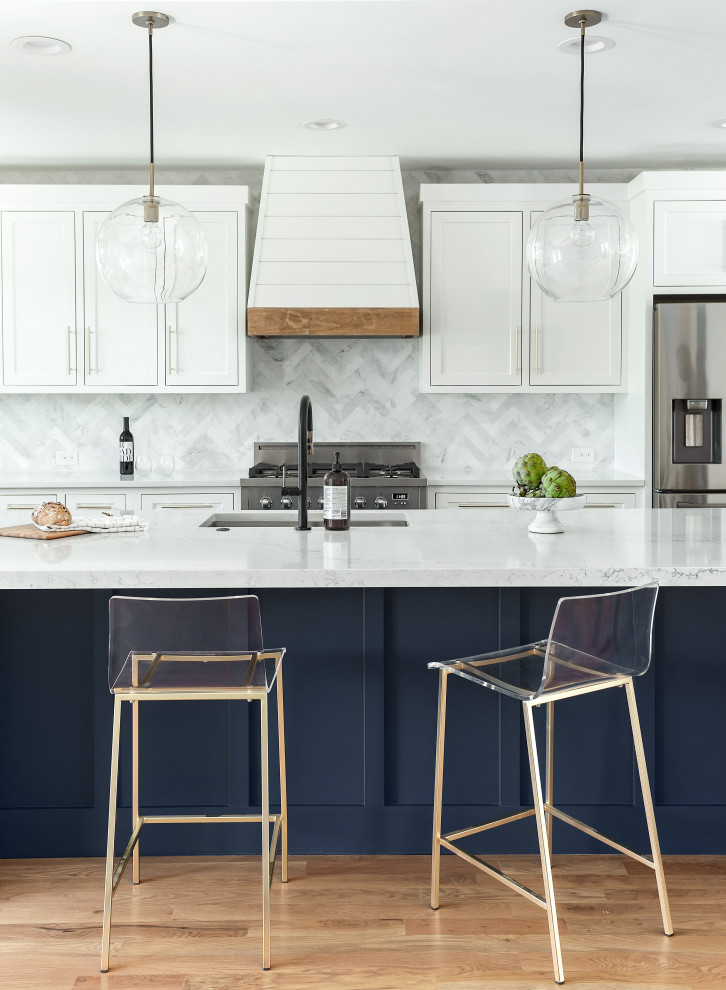 Foto de cocinas en L contemporánea, grande, abierta, con fregadero bajoencimera, armarios estilo shaker, puertas de armario blancas, encimera de cuarzo compacto, salpicadero blanco, salpicadero de mármol, electrodomésticos de acero inoxidable, suelo de madera clara, una isla, suelo marrón y encimeras blancas