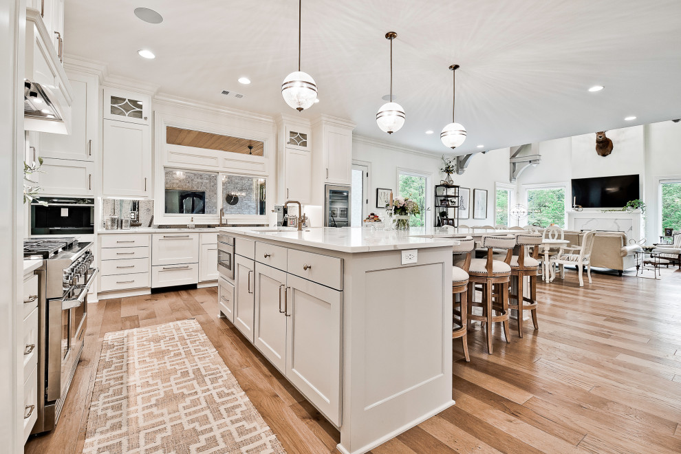 Large transitional light wood floor eat-in kitchen photo in Other with recessed-panel cabinets, white cabinets, quartzite countertops, mirror backsplash, stainless steel appliances, an island and white countertops