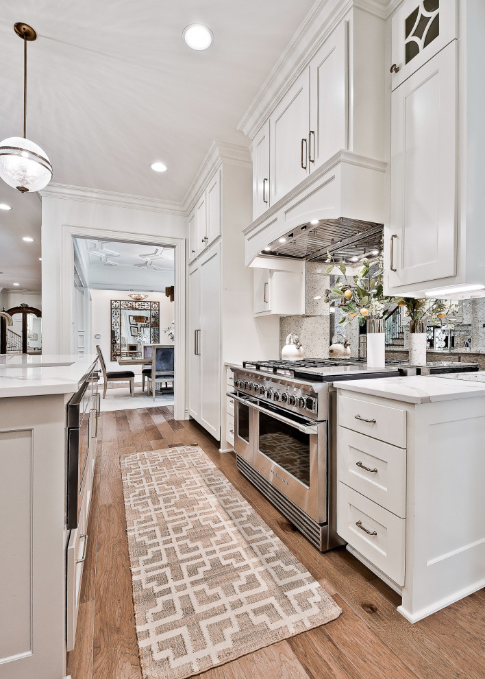 Idéer för att renovera ett stort vintage vit vitt kök och matrum, med luckor med infälld panel, vita skåp, bänkskiva i kvartsit, spegel som stänkskydd, rostfria vitvaror, en köksö och ljust trägolv