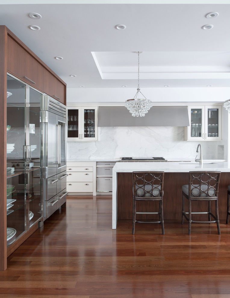 Exempel på ett mellanstort klassiskt kök, med en undermonterad diskho, luckor med infälld panel, vita skåp, marmorbänkskiva, vitt stänkskydd, stänkskydd i sten, rostfria vitvaror, mellanmörkt trägolv och en köksö