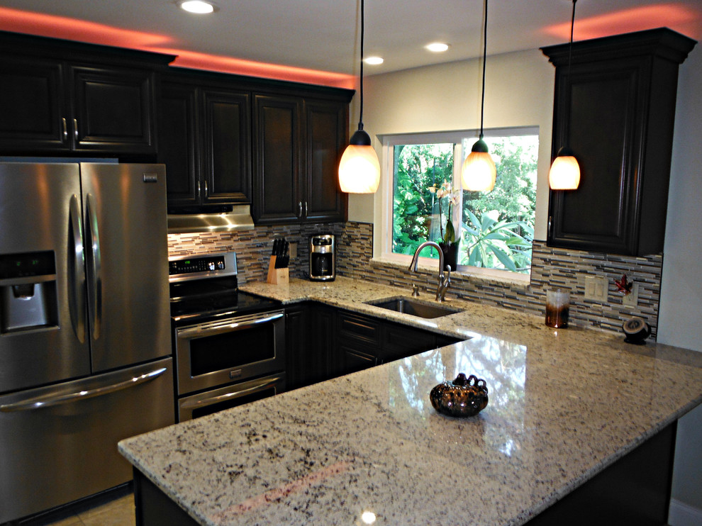 Klassisk inredning av ett litet kök, med en undermonterad diskho, luckor med upphöjd panel, bruna skåp, granitbänkskiva, flerfärgad stänkskydd, stänkskydd i mosaik, rostfria vitvaror, klinkergolv i porslin och en köksö
