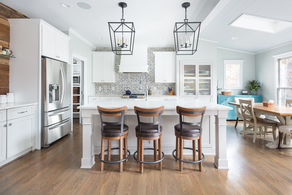 Eat-in kitchen - mid-sized transitional l-shaped porcelain tile and white floor eat-in kitchen idea in Raleigh with an island, an undermount sink, shaker cabinets, white cabinets, multicolored backsplash, porcelain backsplash, stainless steel appliances, wood countertops and white countertops