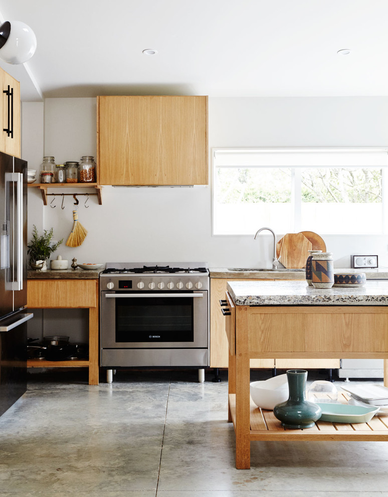 Rustik inredning av ett litet kök, med en dubbel diskho, öppna hyllor, skåp i ljust trä, bänkskiva i betong, rostfria vitvaror, betonggolv och en köksö