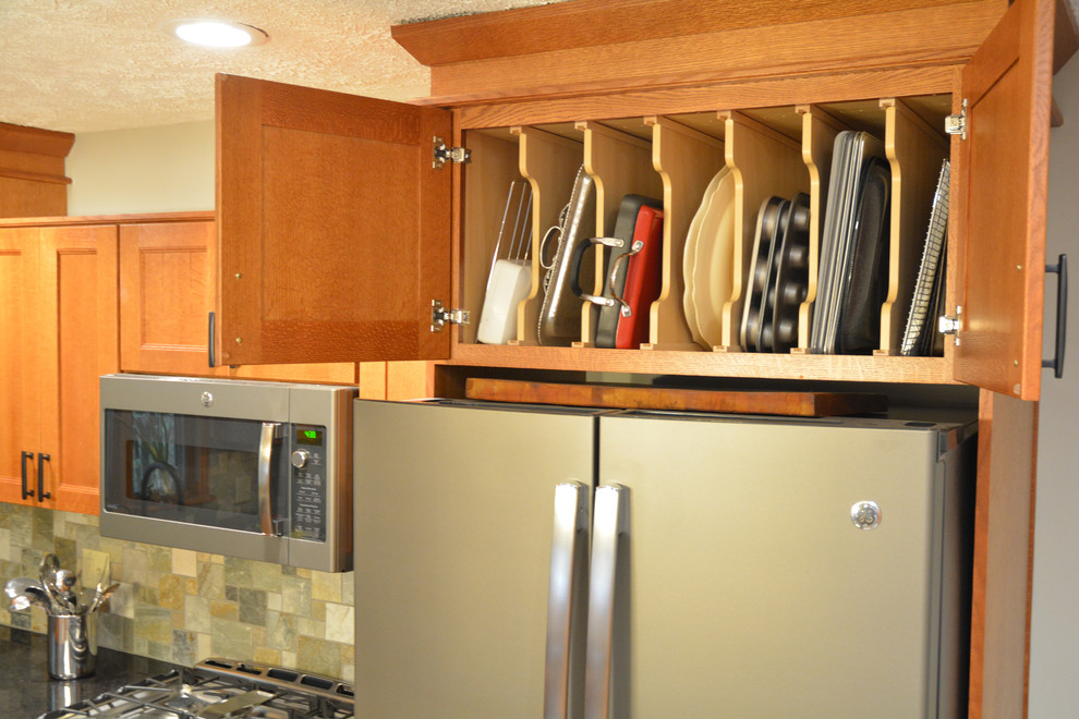 Inredning av ett amerikanskt mellanstort kök, med en undermonterad diskho, skåp i shakerstil, skåp i mellenmörkt trä, bänkskiva i kvarts, flerfärgad stänkskydd, stänkskydd i skiffer, rostfria vitvaror, vinylgolv, en köksö och grått golv