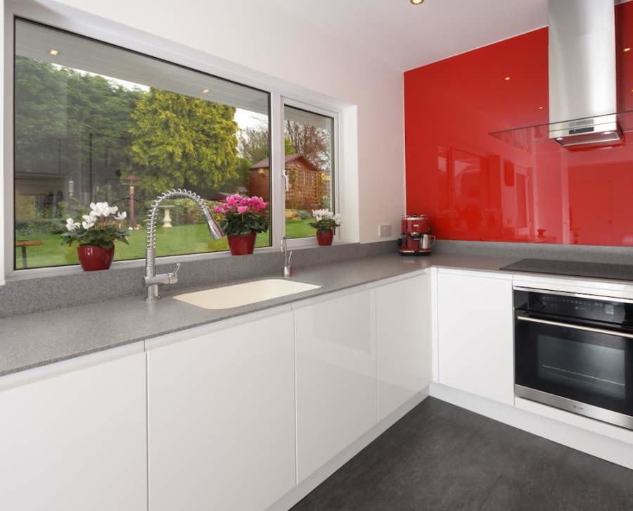 Пример оригинального дизайна: кухня среднего размера в современном стиле с красным фартуком и фартуком из стекла
