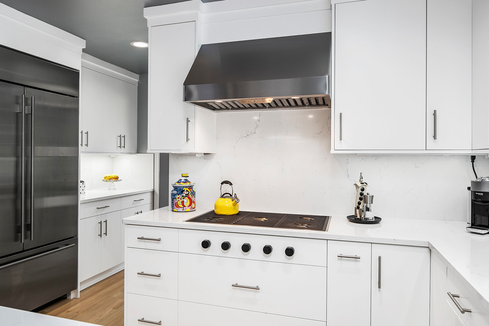 デトロイトにある高級な広いコンテンポラリースタイルのおしゃれなキッチン (アンダーカウンターシンク、フラットパネル扉のキャビネット、白いキャビネット、クオーツストーンカウンター、白いキッチンパネル、石スラブのキッチンパネル、シルバーの調理設備、無垢フローリング、茶色い床、白いキッチンカウンター) の写真