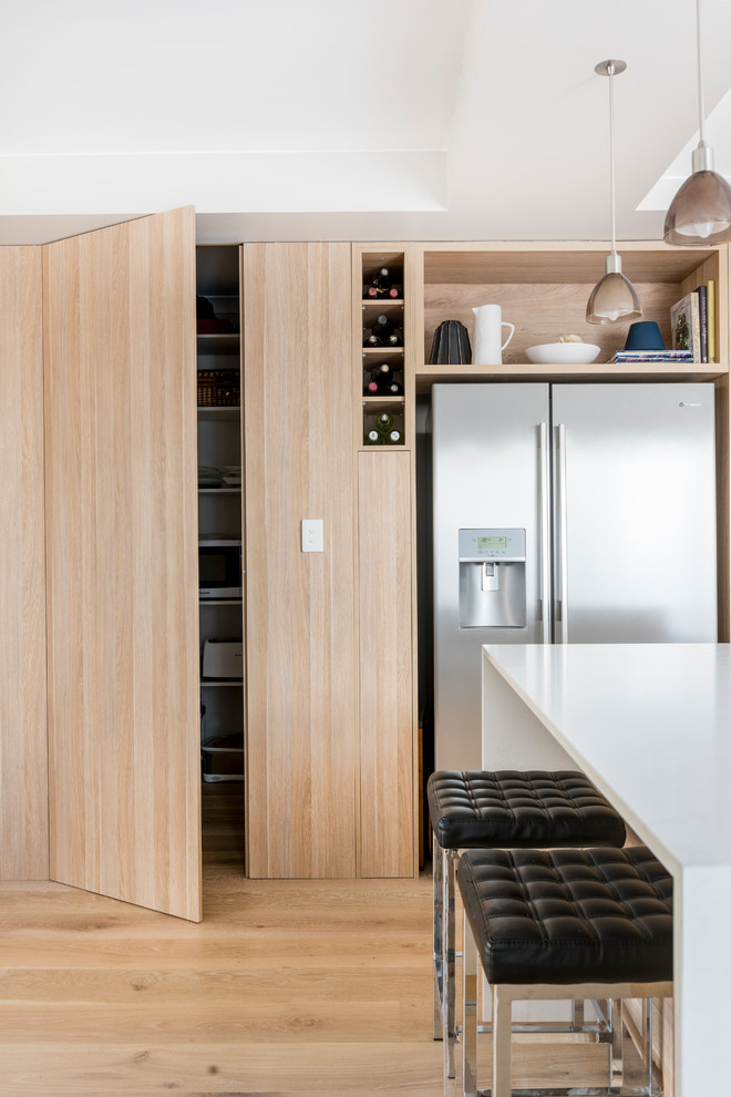 Idées déco pour une cuisine moderne en bois clair de taille moyenne avec un plan de travail en quartz modifié, fenêtre, un électroménager en acier inoxydable, parquet clair et îlot.
