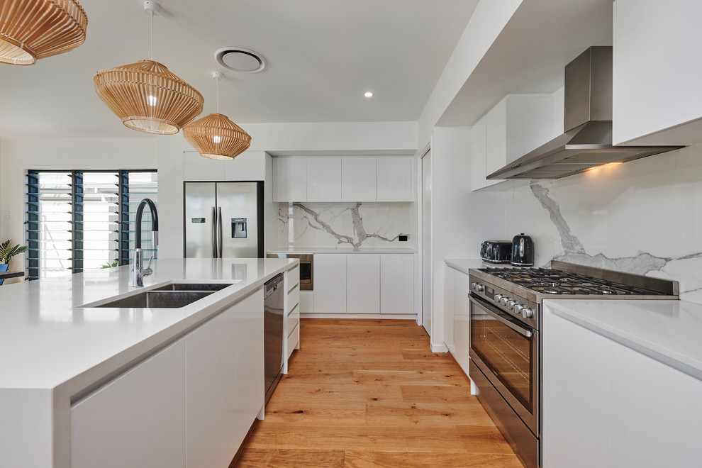 Exempel på ett modernt grå grått kök, med en undermonterad diskho, släta luckor, vita skåp, grått stänkskydd, stänkskydd i sten, rostfria vitvaror, mellanmörkt trägolv, en köksö och brunt golv