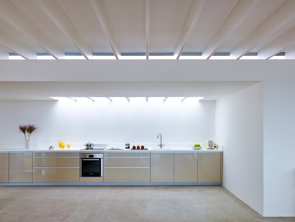 Cette image montre une cuisine ouverte linéaire et encastrable minimaliste en bois clair avec un évier encastré, un placard à porte plane, une crédence blanche et aucun îlot.