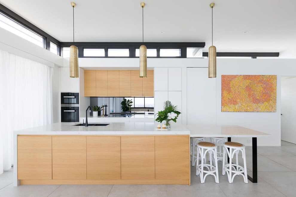 Inspiration for a contemporary galley ceramic tile and gray floor eat-in kitchen remodel in Sydney with black appliances, an undermount sink, flat-panel cabinets, medium tone wood cabinets, mirror backsplash, an island, marble countertops and multicolored countertops