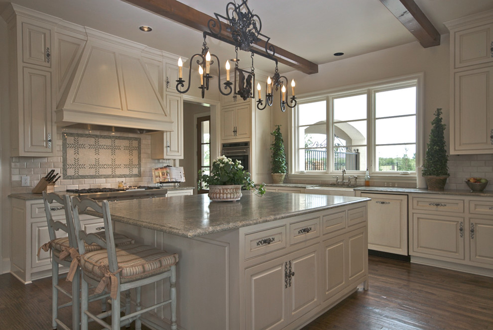 Inspiration for a mid-sized timeless u-shaped medium tone wood floor open concept kitchen remodel in Dallas with a farmhouse sink, raised-panel cabinets, white cabinets, granite countertops, white backsplash, subway tile backsplash, paneled appliances and an island