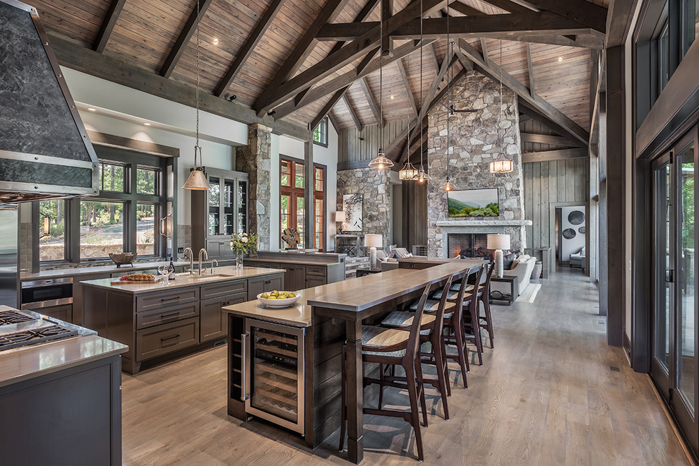 Example of a mountain style light wood floor open concept kitchen design in Other with an undermount sink, glass-front cabinets, brown cabinets, window backsplash, stainless steel appliances, two islands and gray countertops