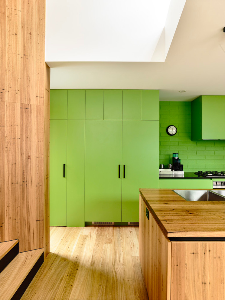 Idee per una piccola cucina contemporanea con lavello a doppia vasca, top in legno, paraspruzzi verde, elettrodomestici in acciaio inossidabile e parquet chiaro