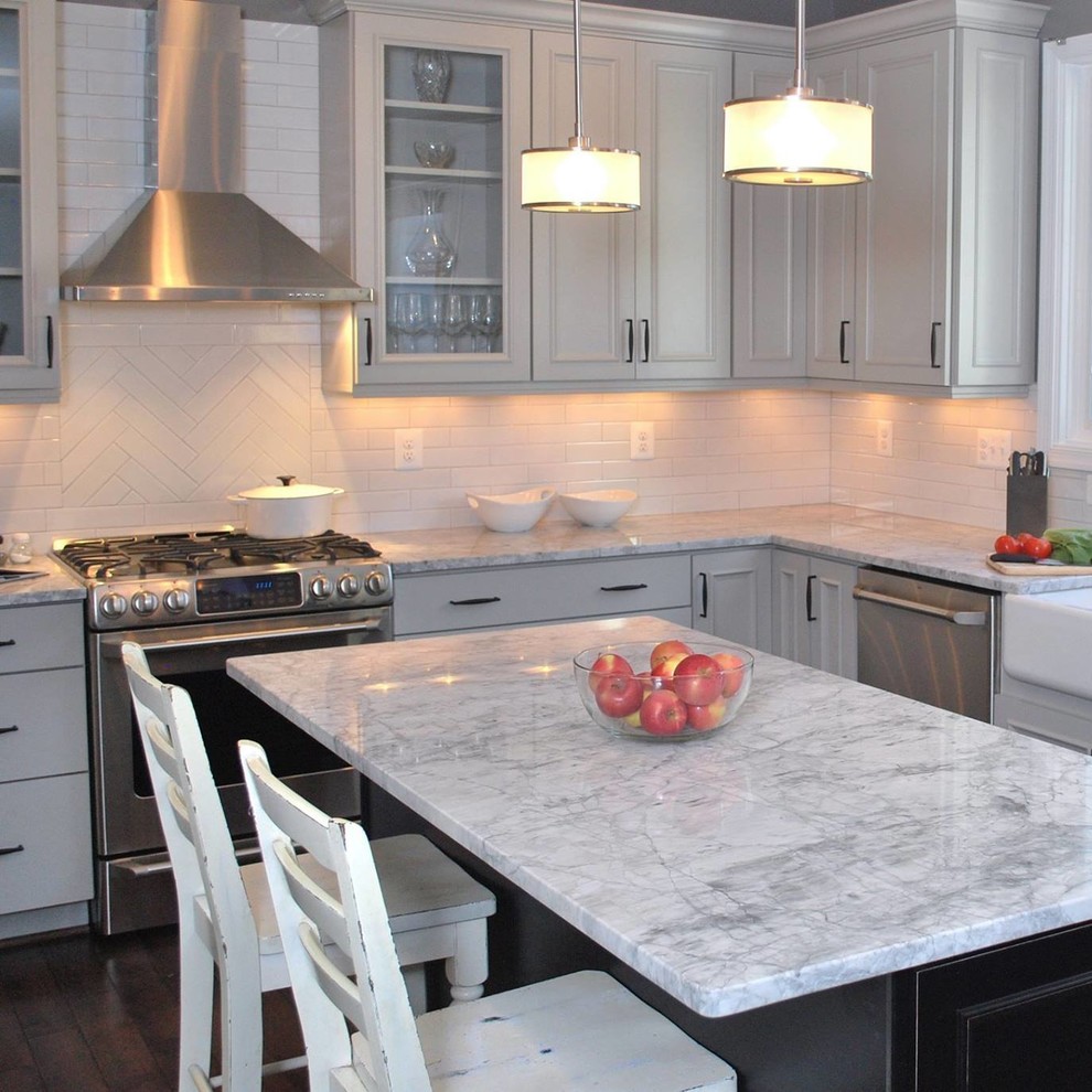 Inspiration for a mid-sized transitional u-shaped dark wood floor eat-in kitchen remodel in DC Metro with a farmhouse sink, recessed-panel cabinets, gray cabinets, quartzite countertops, white backsplash, porcelain backsplash, stainless steel appliances and an island