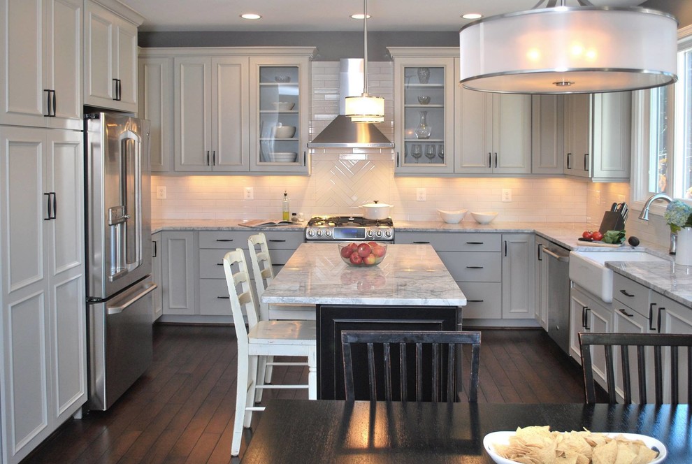 Mid-sized transitional u-shaped dark wood floor eat-in kitchen photo in DC Metro with a farmhouse sink, recessed-panel cabinets, gray cabinets, quartzite countertops, white backsplash, porcelain backsplash, stainless steel appliances and an island