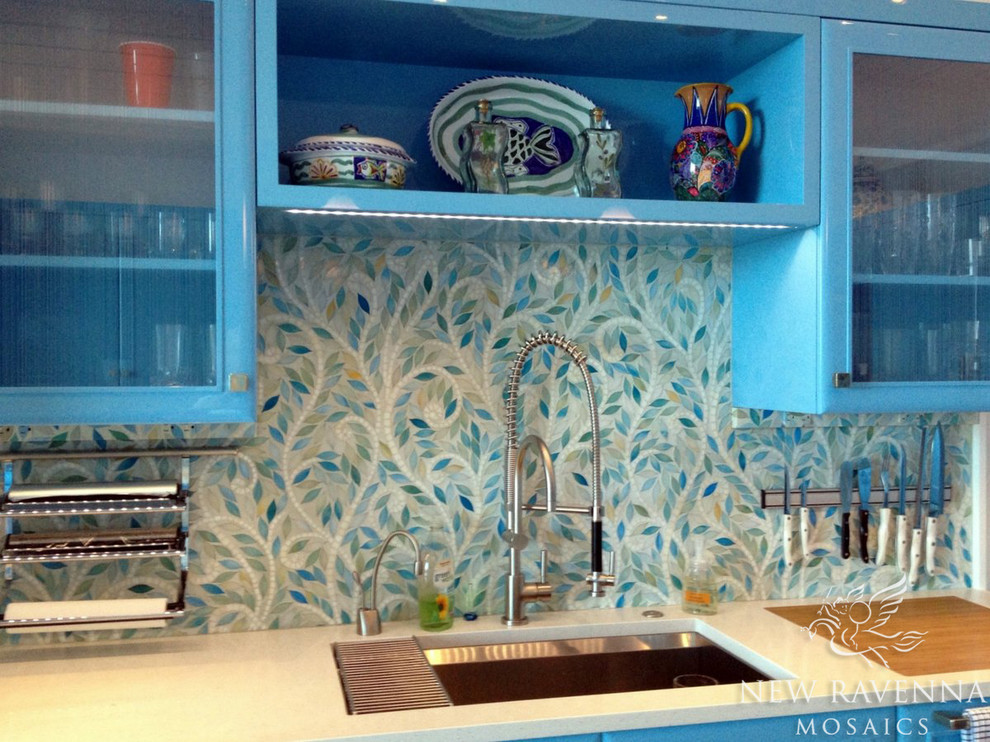 Aménagement d'une cuisine éclectique avec un évier encastré, un placard à porte vitrée, des portes de placard bleues, un plan de travail en granite et une crédence multicolore.