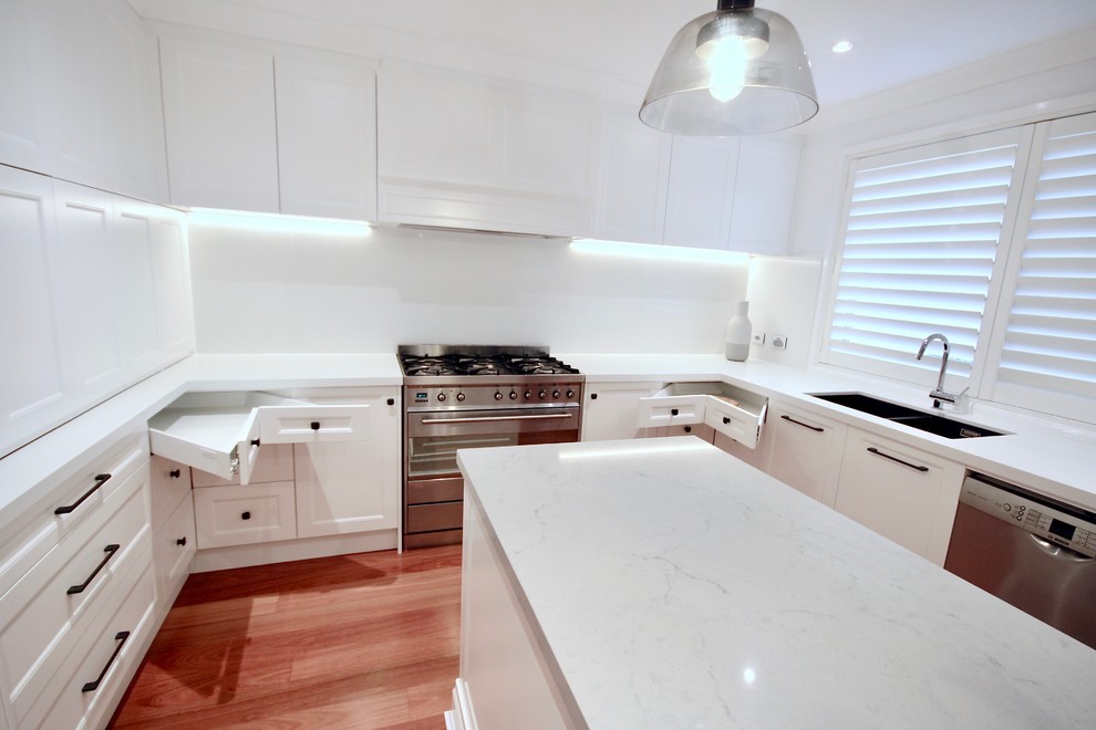 Example of a large transitional u-shaped medium tone wood floor and brown floor eat-in kitchen design in Sydney with an undermount sink, recessed-panel cabinets, white cabinets, quartz countertops, white backsplash, stone slab backsplash, stainless steel appliances, an island and white countertops