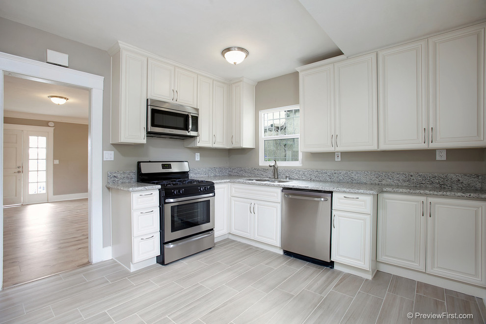 Example of a small arts and crafts u-shaped porcelain tile kitchen design in San Diego with an undermount sink, raised-panel cabinets, white cabinets, granite countertops, gray backsplash, stone slab backsplash and stainless steel appliances