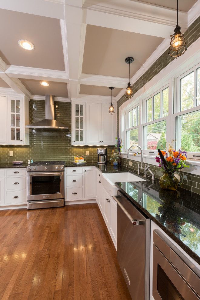 Inspiration for a mid-sized transitional l-shaped medium tone wood floor enclosed kitchen remodel in Columbus with a farmhouse sink, beaded inset cabinets, white cabinets, granite countertops, green backsplash, glass tile backsplash, stainless steel appliances and no island