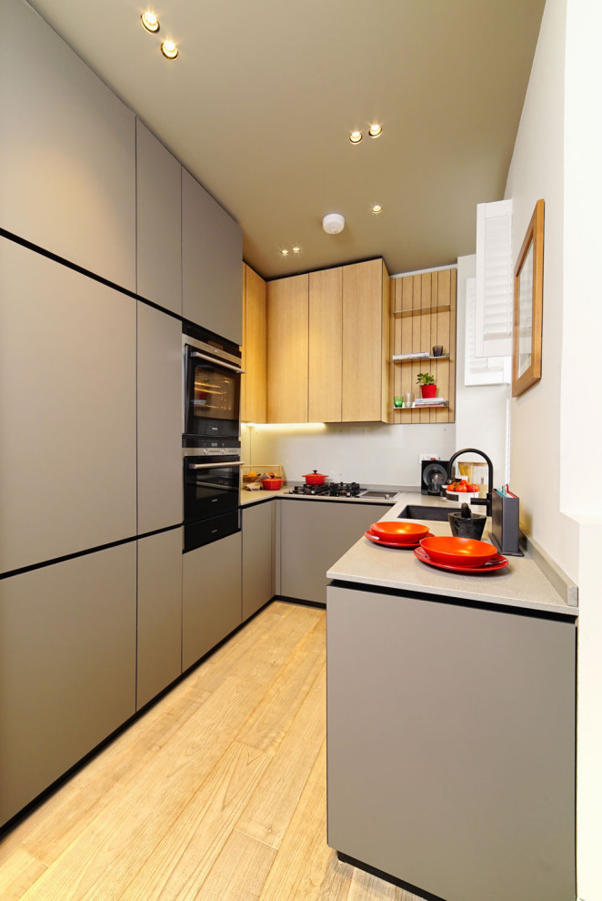 This is an example of a medium sized contemporary l-shaped kitchen in London with a submerged sink, flat-panel cabinets, grey cabinets, integrated appliances, light hardwood flooring, no island, beige floors and grey worktops.