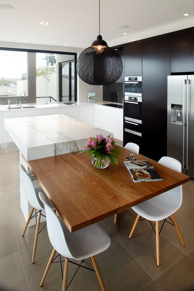 Mid-sized trendy l-shaped porcelain tile enclosed kitchen photo in Sydney with flat-panel cabinets, black cabinets, marble countertops, glass sheet backsplash, stainless steel appliances and an island