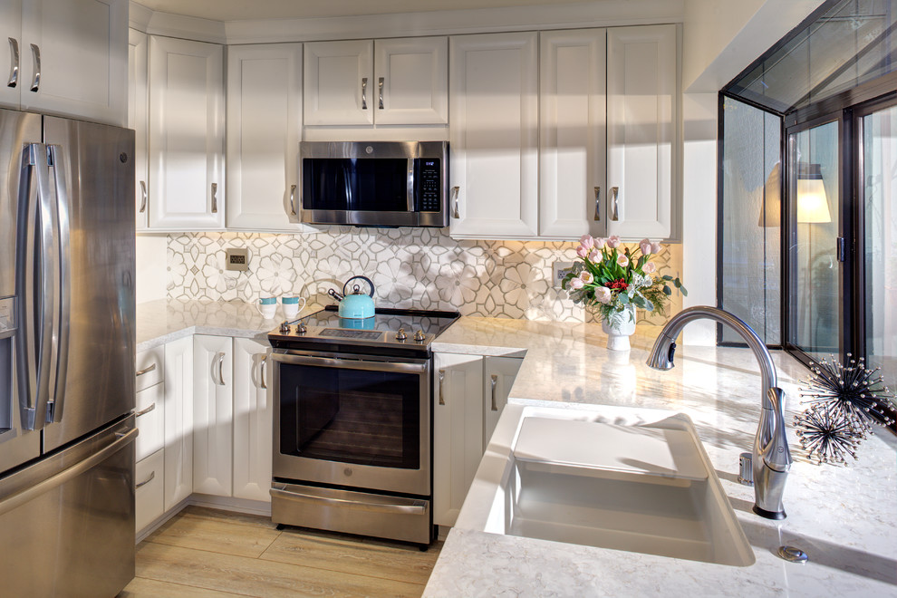 Photo of a small classic u-shaped kitchen/diner in Sacramento with a belfast sink, recessed-panel cabinets, white cabinets, engineered stone countertops, white splashback, mosaic tiled splashback, stainless steel appliances, vinyl flooring, an island, grey floors and white worktops.