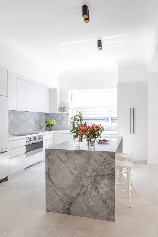 Modern inredning av ett mellanstort grå grått kök, med en undermonterad diskho, vita skåp, marmorbänkskiva, grått stänkskydd, stänkskydd i marmor, rostfria vitvaror, klinkergolv i keramik, en köksö och beiget golv