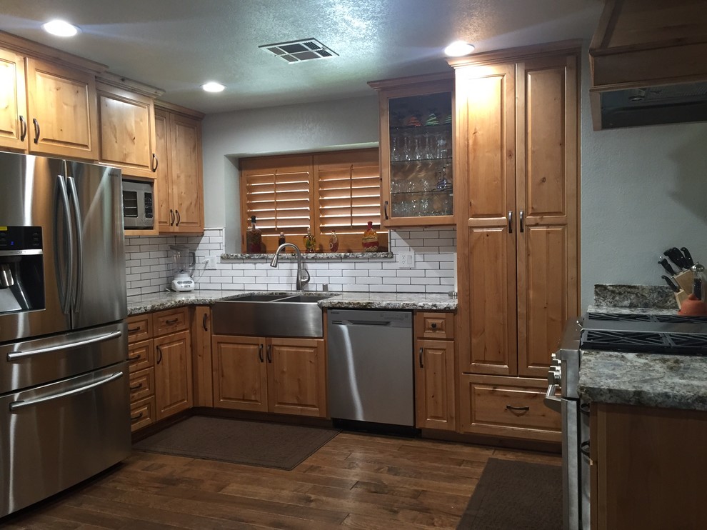 Bild på ett mellanstort rustikt u-kök, med en undermonterad diskho, luckor med upphöjd panel, skåp i ljust trä, granitbänkskiva, vitt stänkskydd, stänkskydd i keramik, rostfria vitvaror och mellanmörkt trägolv