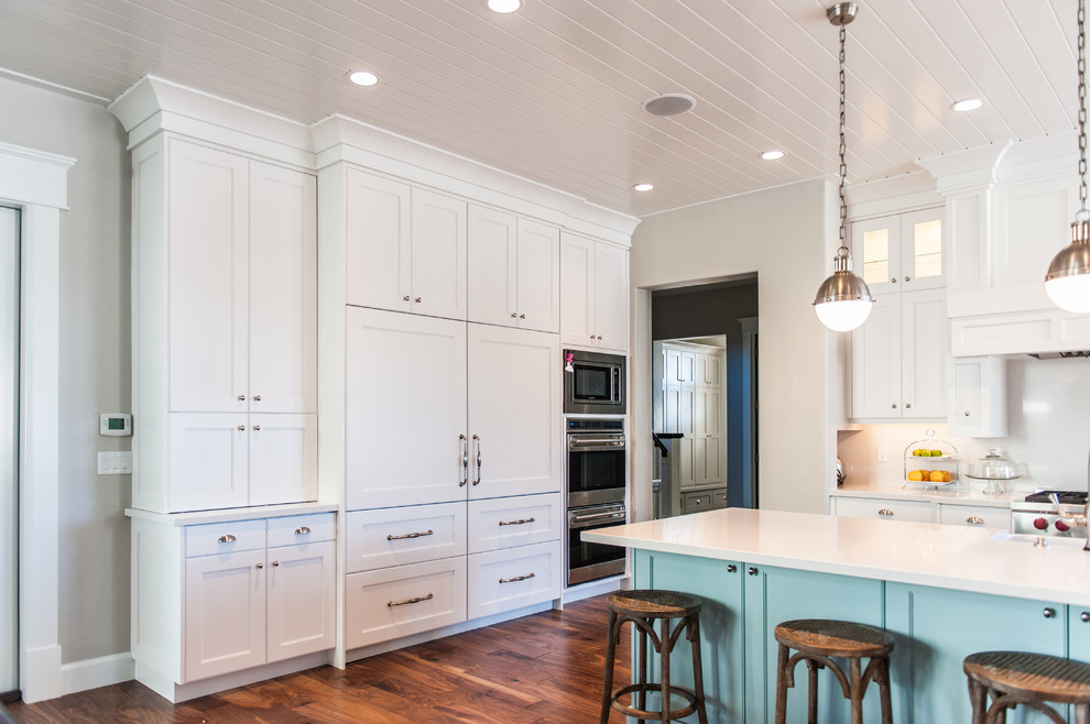 Example of a large transitional u-shaped medium tone wood floor and brown floor eat-in kitchen design in Salt Lake City with an undermount sink, shaker cabinets, white cabinets, quartz countertops, white backsplash, stainless steel appliances and an island