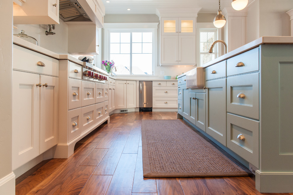 Example of a large transitional u-shaped medium tone wood floor and brown floor eat-in kitchen design in Salt Lake City with an undermount sink, shaker cabinets, white cabinets, quartz countertops, white backsplash, stainless steel appliances and an island
