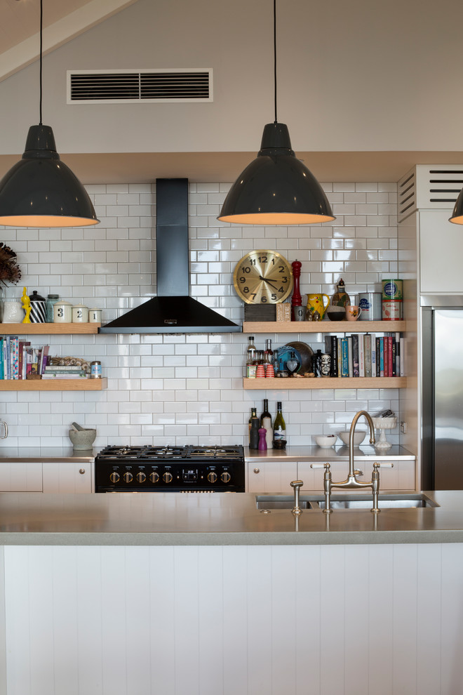 Foto på ett mellanstort lantligt grå kök, med en undermonterad diskho, släta luckor, vita skåp, bänkskiva i betong, vitt stänkskydd, stänkskydd i tunnelbanekakel, svarta vitvaror och en köksö
