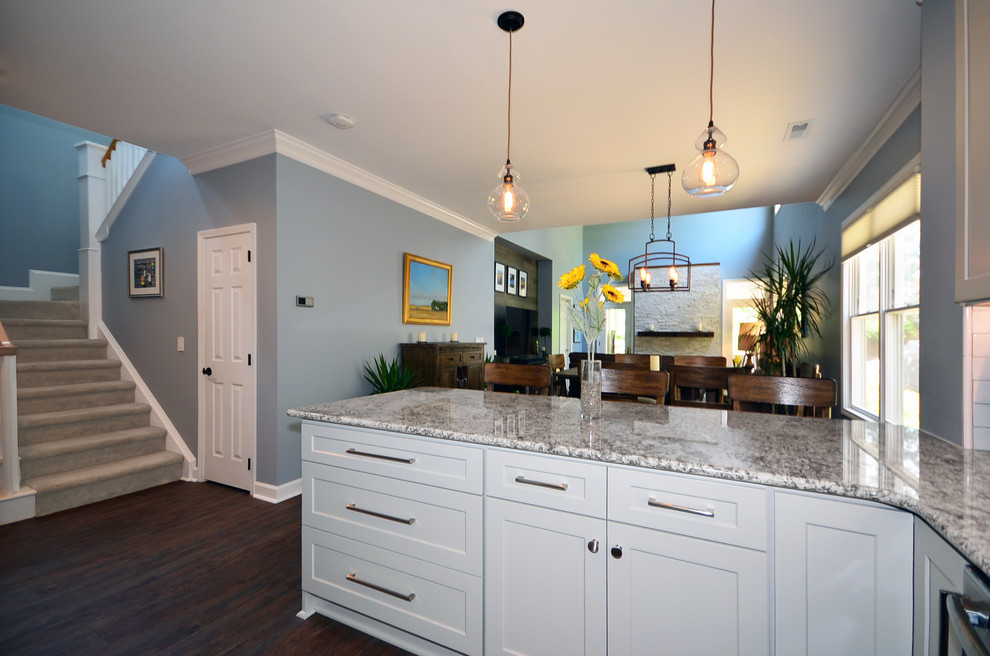 Example of a mid-sized beach style galley vinyl floor and brown floor eat-in kitchen design in Charlotte with a farmhouse sink, shaker cabinets, gray cabinets, granite countertops, white backsplash, ceramic backsplash, stainless steel appliances, a peninsula and multicolored countertops