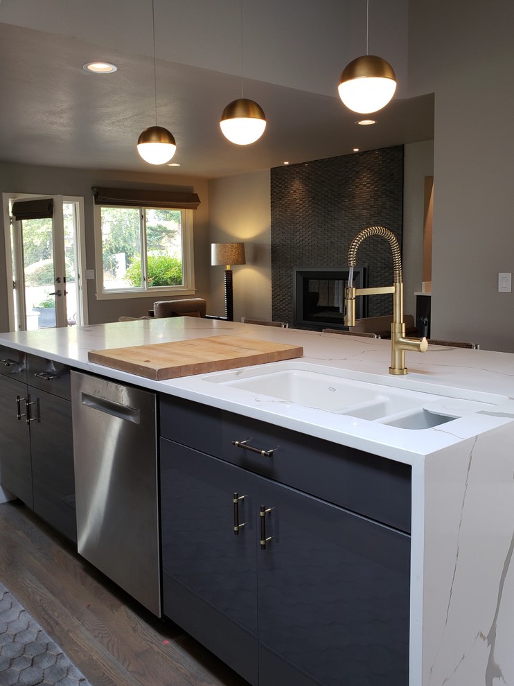 Photo of a large modern l-shaped open plan kitchen in Seattle with a submerged sink, flat-panel cabinets, grey cabinets, engineered stone countertops, multi-coloured splashback, glass tiled splashback, stainless steel appliances, medium hardwood flooring, an island, brown floors and white worktops.