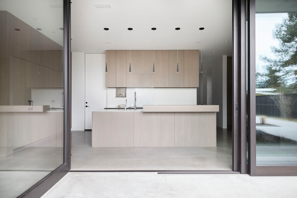 Esempio di una grande cucina moderna con lavello sottopiano, ante lisce, ante grigie, top in superficie solida, paraspruzzi bianco, pavimento in cemento e top bianco