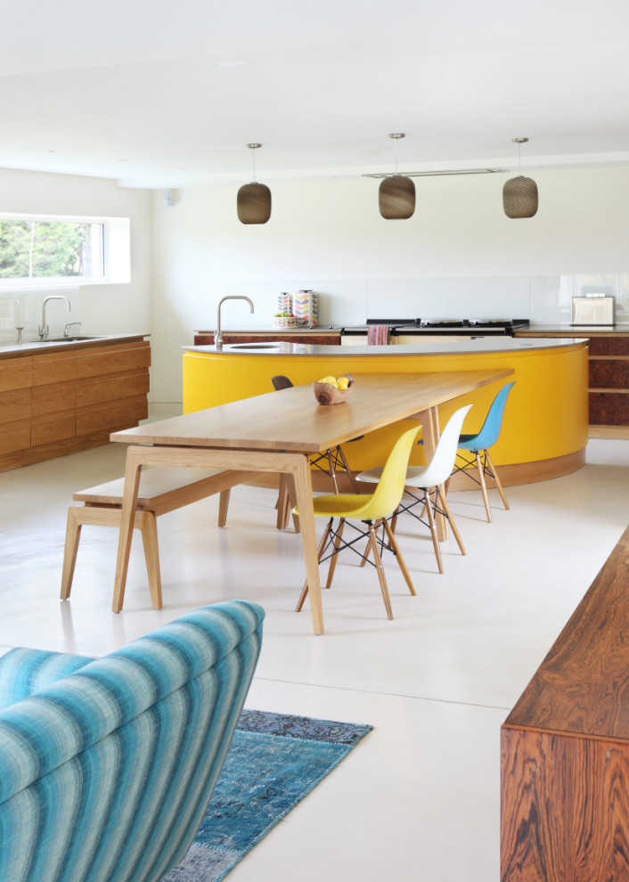 Large contemporary l-shaped open plan kitchen in Oxfordshire with a submerged sink, flat-panel cabinets, medium wood cabinets, glass sheet splashback, integrated appliances, an island and beige floors.