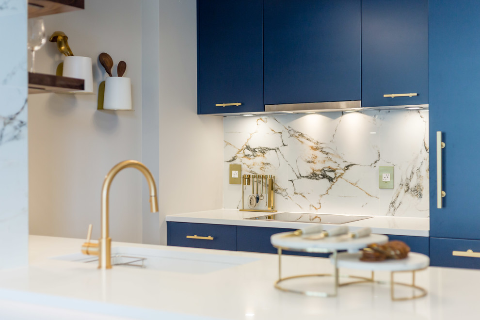 Photo of a medium sized contemporary galley kitchen/diner in Vancouver with a submerged sink, flat-panel cabinets, blue cabinets, composite countertops, white splashback, marble splashback, integrated appliances, dark hardwood flooring, a breakfast bar, brown floors and white worktops.