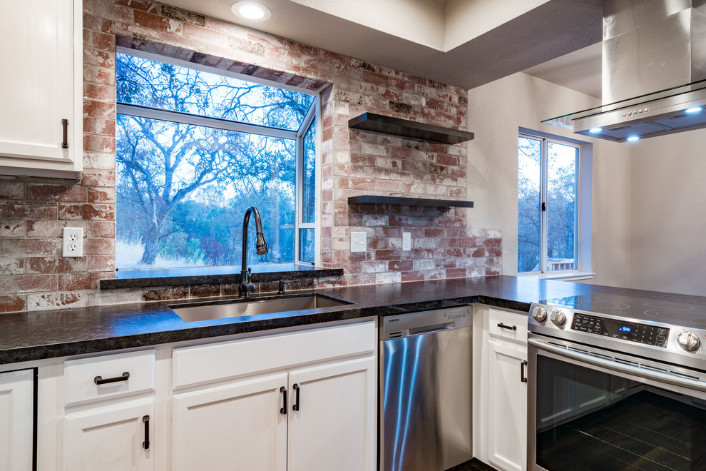 Bild på ett avskilt, mellanstort vintage u-kök, med en trippel diskho, luckor med infälld panel, vita skåp, granitbänkskiva, rött stänkskydd, stänkskydd i tegel, rostfria vitvaror, mörkt trägolv, en halv köksö och brunt golv