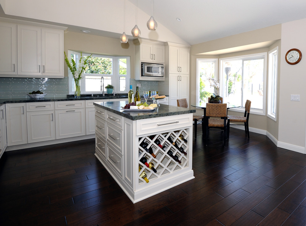 Example of a mid-sized transitional l-shaped dark wood floor open concept kitchen design in Orange County with an undermount sink, shaker cabinets, white cabinets, granite countertops, green backsplash, glass sheet backsplash, stainless steel appliances and an island