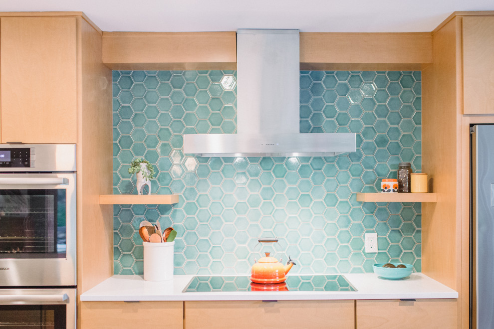 Foto på ett stort retro vit linjärt kök och matrum, med en undermonterad diskho, skåp i ljust trä, blått stänkskydd, stänkskydd i keramik, rostfria vitvaror, ljust trägolv och en köksö