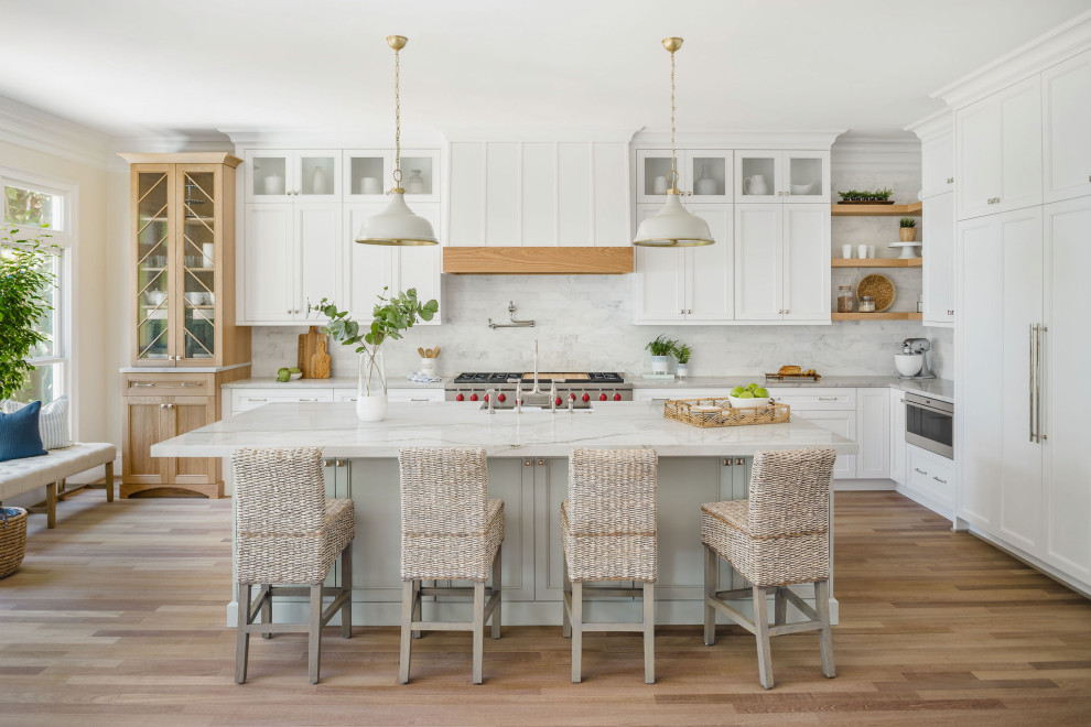 Maritim inredning av ett vit vitt kök, med skåp i shakerstil, vita skåp, stänkskydd i marmor, en köksö, en rustik diskho, grått stänkskydd, integrerade vitvaror, mellanmörkt trägolv och brunt golv
