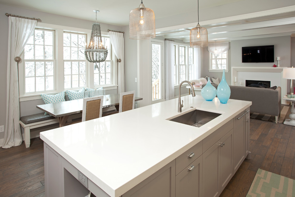 Стильный дизайн: серо-белая кухня-гостиная в морском стиле с одинарной мойкой, столешницей из кварцевого агломерата и серыми фасадами - последний тренд