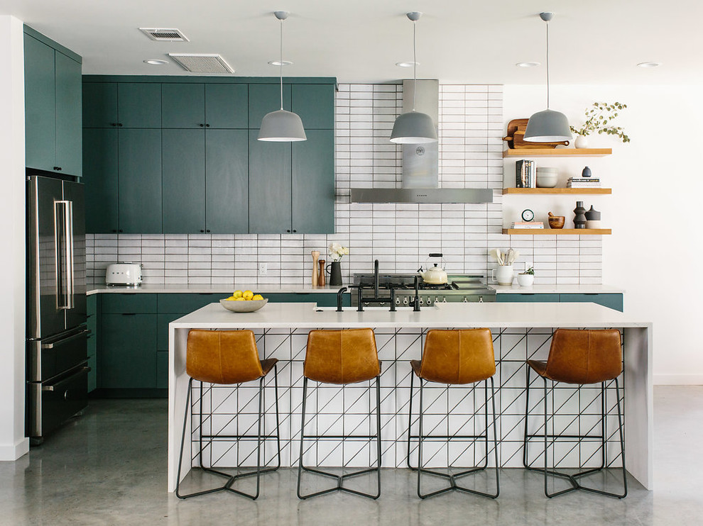 Example of a mid-sized trendy l-shaped concrete floor and gray floor kitchen design in Austin with a farmhouse sink, flat-panel cabinets, green cabinets, quartzite countertops, white backsplash, brick backsplash, stainless steel appliances, an island and white countertops