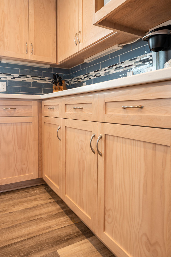 Example of a mid-sized beach style l-shaped laminate floor and beige floor eat-in kitchen design in San Luis Obispo with a drop-in sink, shaker cabinets, light wood cabinets, quartz countertops, blue backsplash, ceramic backsplash, stainless steel appliances, an island and multicolored countertops