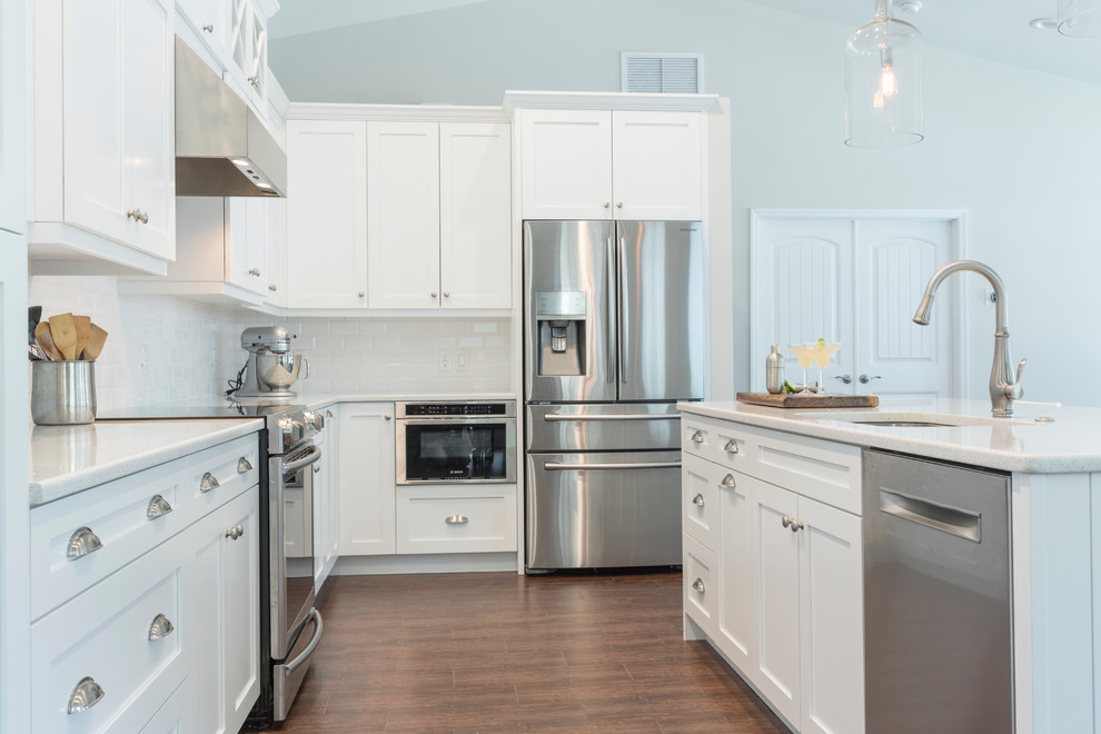 Example of a large transitional l-shaped porcelain tile eat-in kitchen design in Tampa with an undermount sink, shaker cabinets, white cabinets, quartz countertops, white backsplash, porcelain backsplash, stainless steel appliances and an island