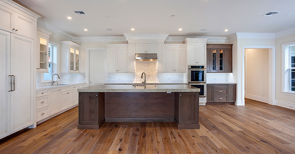 Large traditional l-shaped open plan kitchen in Miami with a submerged sink, white cabinets, integrated appliances, medium hardwood flooring and an island.