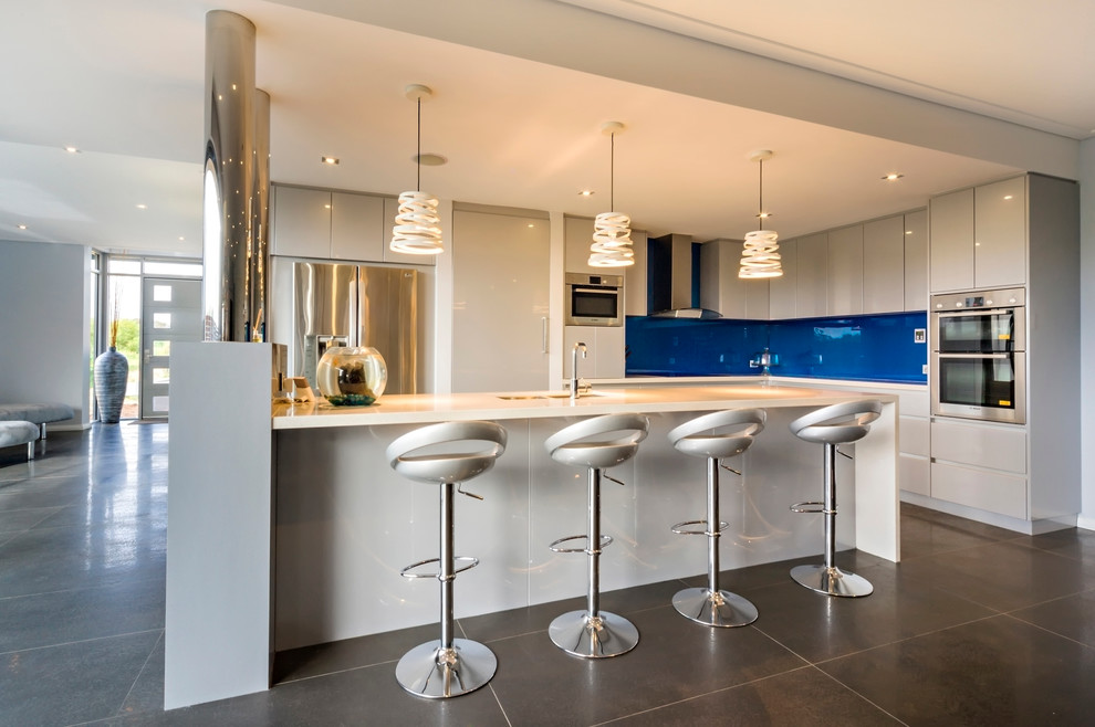 Foto di un cucina con isola centrale design con ante lisce, ante bianche, paraspruzzi blu e elettrodomestici in acciaio inossidabile