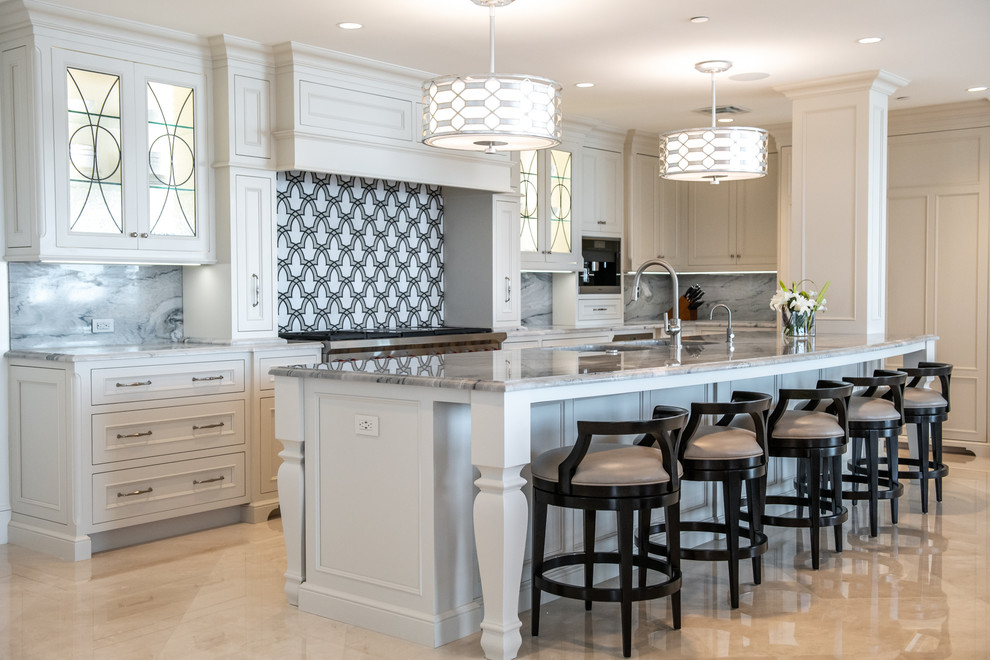 Beach style kitchen in Tampa with white cabinets, marble worktops, an island, beige floors, multi-coloured splashback, stainless steel appliances, grey worktops and recessed-panel cabinets.