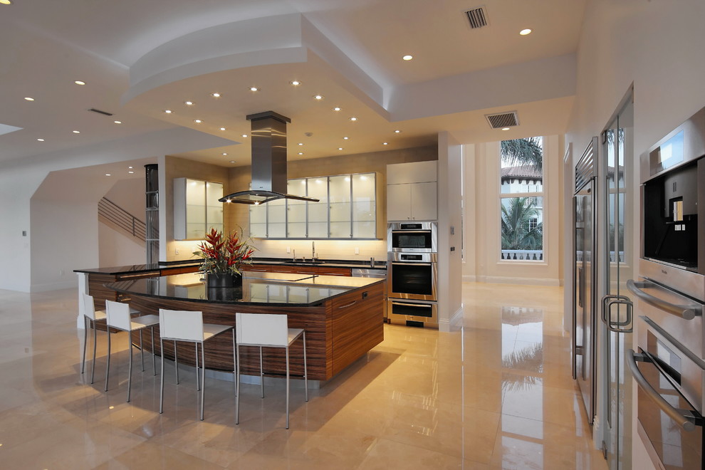 Inspiration for a contemporary l-shaped kitchen in Tampa with flat-panel cabinets, dark wood cabinets, stainless steel appliances, an island and beige floors.