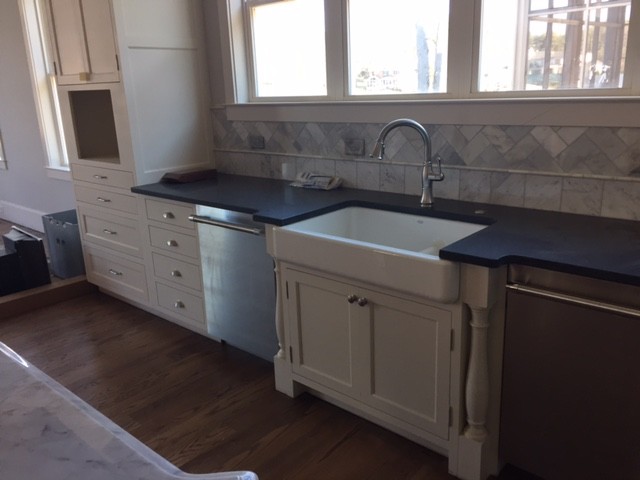 Inspiration for a large timeless l-shaped medium tone wood floor and brown floor eat-in kitchen remodel in Charlotte with a farmhouse sink, recessed-panel cabinets, white cabinets, solid surface countertops, yellow backsplash, stone tile backsplash, paneled appliances and an island