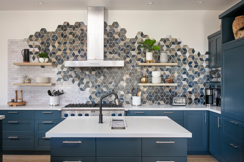 Inspiration for a nautical l-shaped kitchen in Other with a submerged sink, shaker cabinets, blue cabinets, multi-coloured splashback, stainless steel appliances, light hardwood flooring, an island and white worktops.